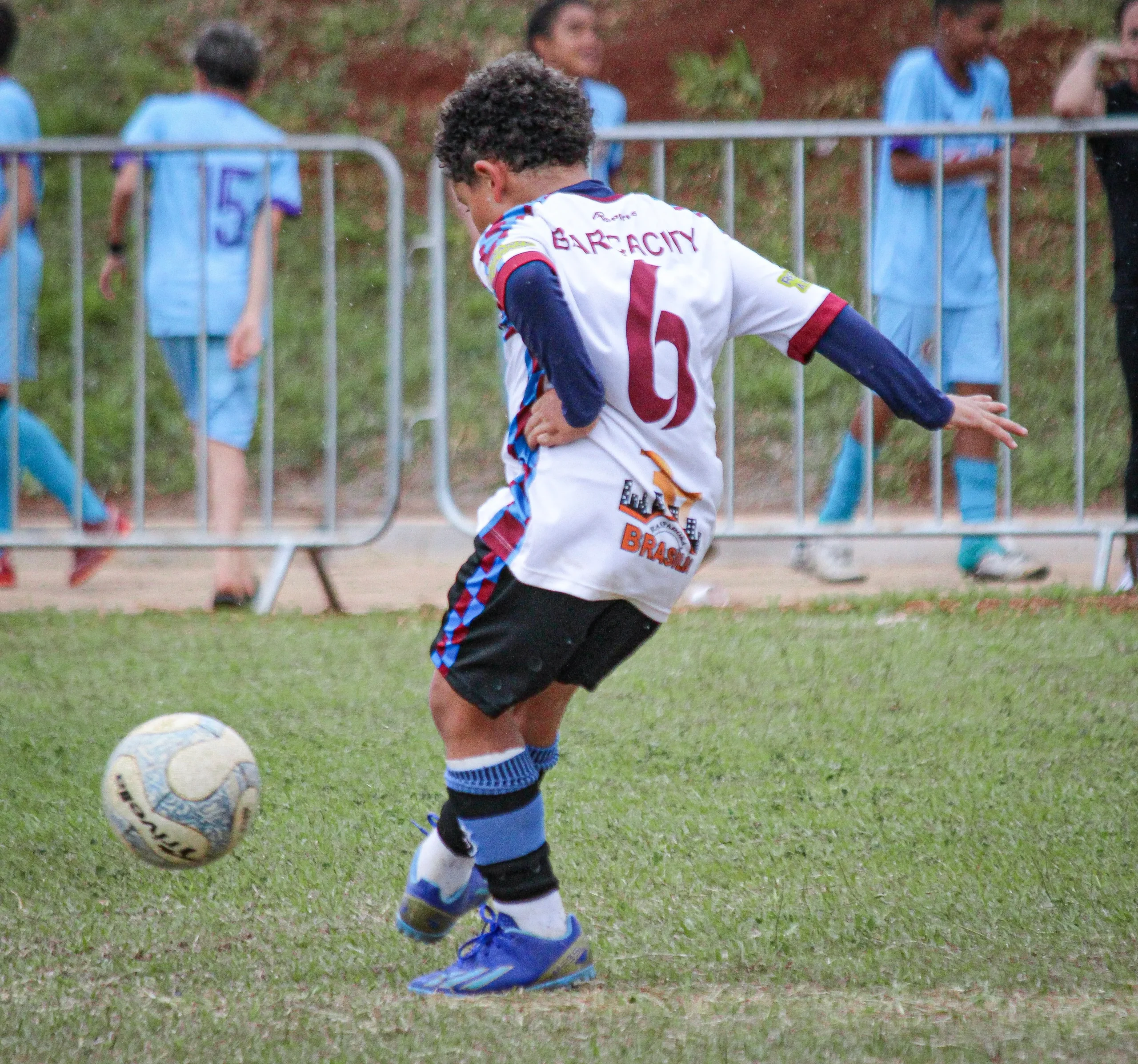 fundamentos do futebol infantil com criança dominando a bola em campo