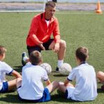 Treinador orientando crianças no futebol infantil com foco em inteligência emocional