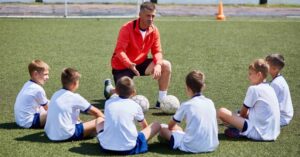 Treinador orientando crianças no futebol infantil com foco em inteligência emocional