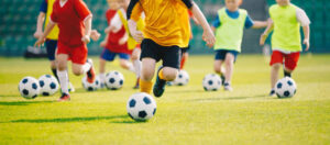 Jogadores em um torneio infantil de futebol, representando a busca precoce por destaque no futebol.