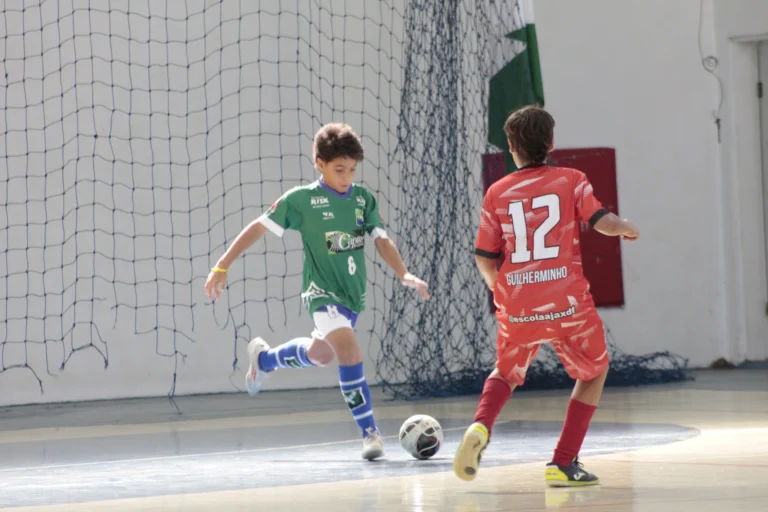 Menino sub-12 praticando passadas firmes no futsal, aprimorando equilíbrio e velocidade defensiva na quadra.
