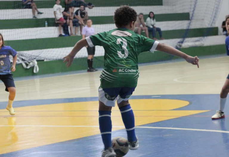 a boy in a green jersey kicking a football ball