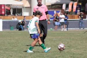 Jovem atleta Sub-12 em ação durante campeonato de futebol, representando foco e desenvolvimento emocional.