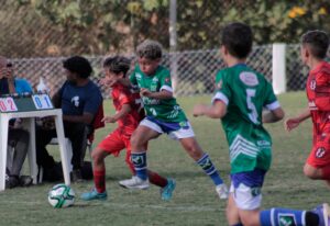 Crianças disputando partida de campeonato de futebol infantil