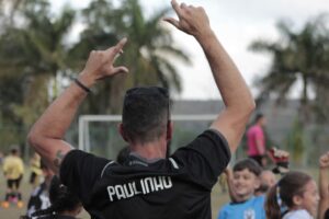 Pai acompanha filho em campeonato de futebol infantil, promovendo valores positivos no esporte