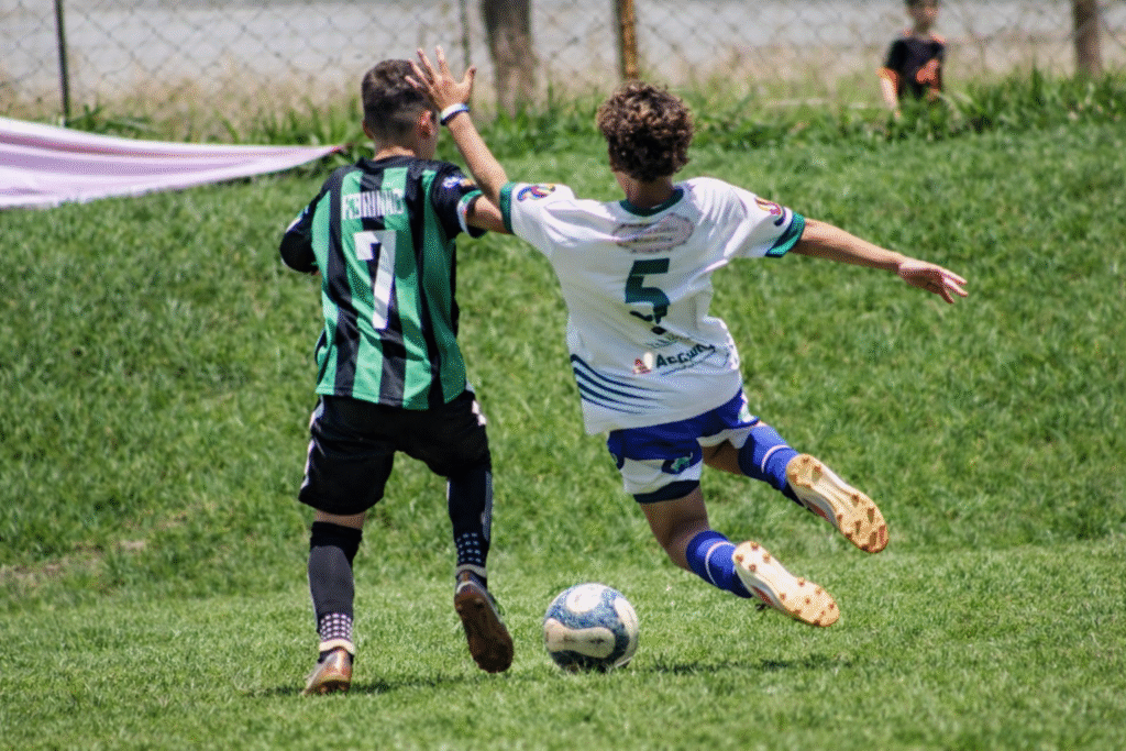 
Disputa de bola no futebol infantil: cada ação em campo contribui para o desenvolvimento técnico, emocional e social da criança.