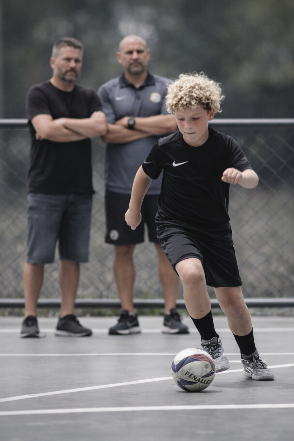 Criança jogando futebol infantil sob observação de adultos, representando o isolamento emocional causado pela pressão e pela comparação no esporte