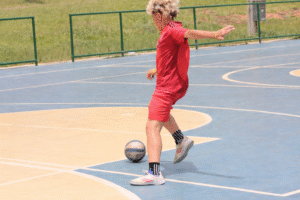 Criança jogando futebol infantil demonstrando leitura de jogo em quadra esportiva.