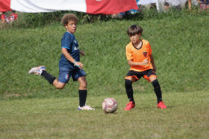 Crianças jogando futebol infantil em ação coletiva valorizando o passe